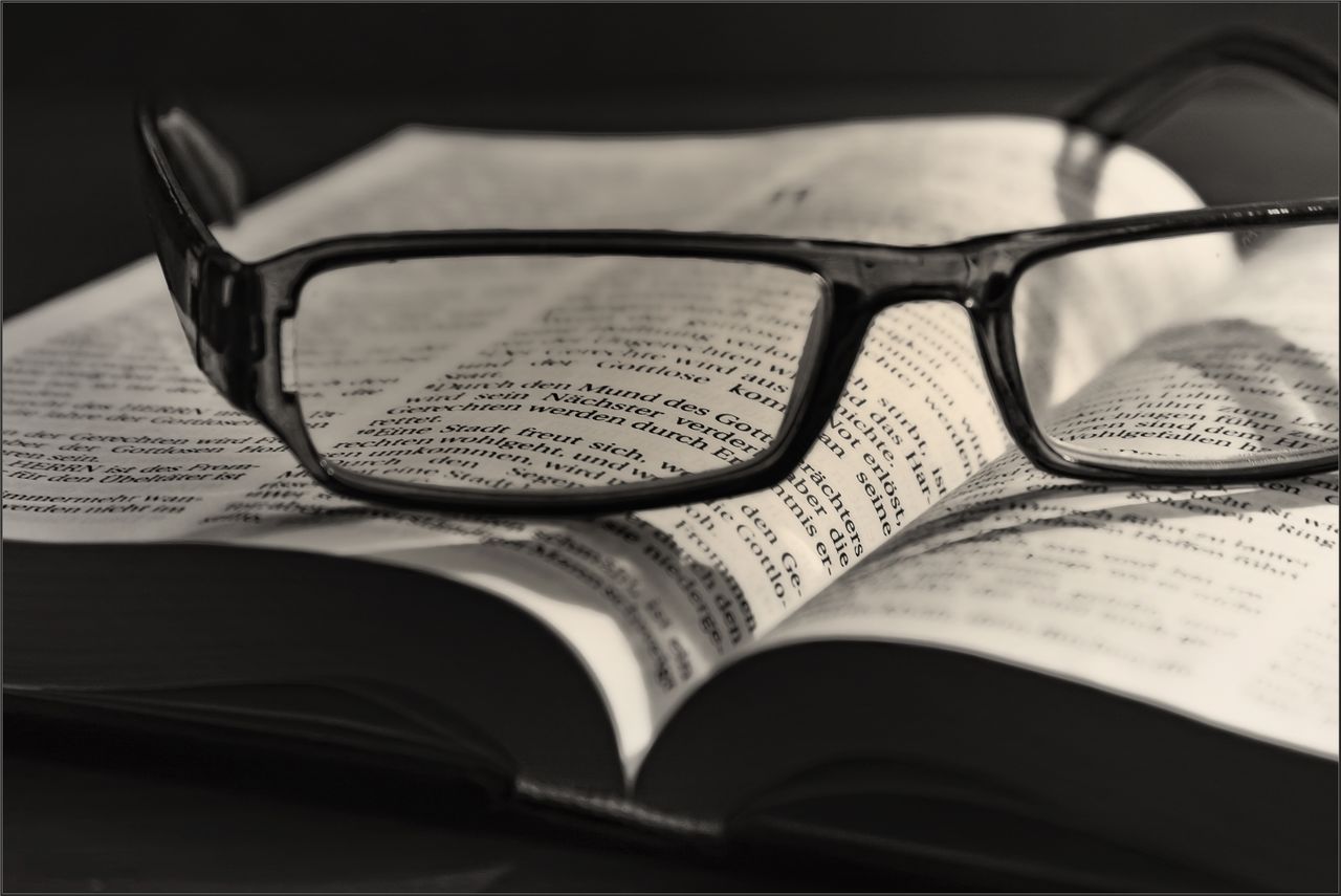 Services Artistic black and white image of eyeglasses resting on an open book. Ideal for literature or vision concepts.